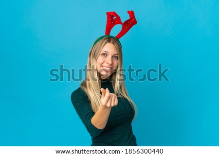 Woman with christmas hat isolated on blue background making money gesture