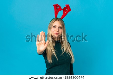 Woman with christmas hat isolated on blue background making stop gesture