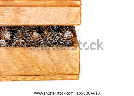 cones with Christmas toys in a wooden decorative box on a white background