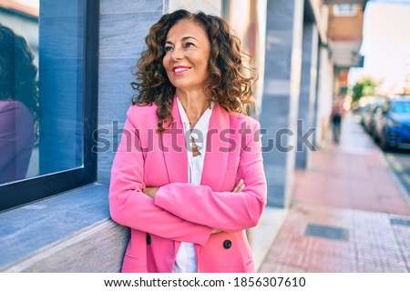 Middle age hispanic businesswoman smiling happy standing at the city.