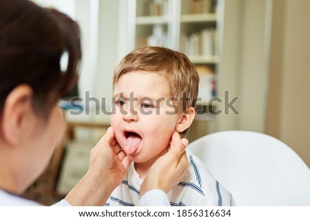 Pediatrician feels the tonsils in a child with a sore throat and shows his tongue Royalty-Free Stock Photo #1856316634