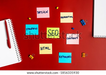 The word " SEO " from colored sticky notes on a red table. Search engine optimization and business concept and strategy