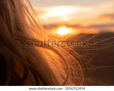 VIEW FROM BEHIND THE HEAD OF A BLOND WOMAN LOOKING AT SUNSET ON A HILL IN CONSUEGRA, SPAIN