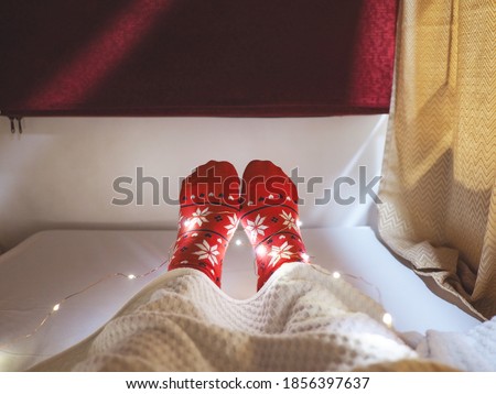 Tourist wearing red socks with Christmas pattern selfie feet  on bed at hotel capsule. Happy vacation on X'mas holiday concept.