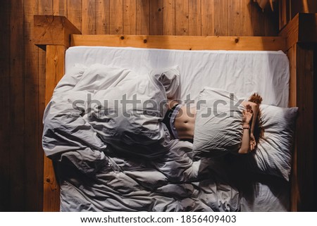 Woman in the bed covering her face with pillow. Wake up, lazy morning