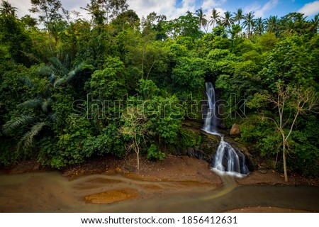 Waterfall landscape. Beautiful waterfall in Ubud. Tropical scenery. Slow shutter speed, motion photography. Nature background. Horizontal layout. Bali, Indonesia