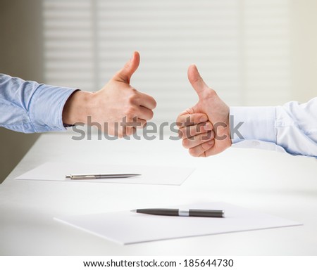 Successful business people showing thumbs up sign after making agreement