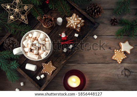 Christmas composition with hot drink, marshmallow, gingerbread cookies and candles on  wooden table, top view, copy space. Christmas and winter holidays coziness concept.