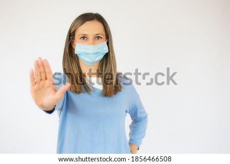 Portrait of young woman, saying no to coronavirus infection with wearing medical surgical blue face mask isolated on white background