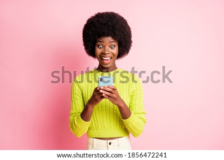 Photo portrait of excited girl typing holding phone in two hands isolated on pastel pink colored background