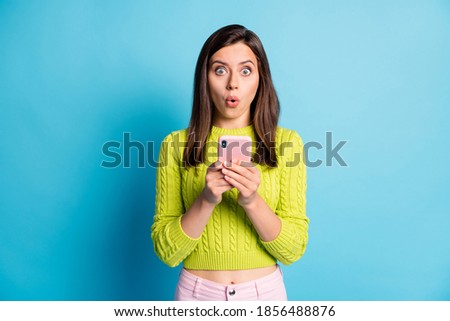 Photo of young girl amazed shocked surprised fake novelty news rumor chat mobile cellphone isolated over blue color background Royalty-Free Stock Photo #1856488876