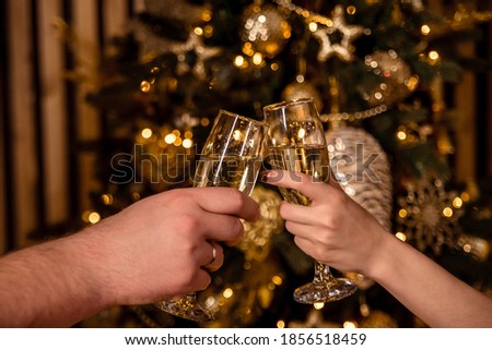 Close-up of two glasses with champagne bubbles in their hands, tilted towards each other on a light background. The concept of a romantic evening and dinner in a restaurant. Advertising space