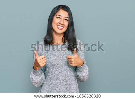 Beautiful asian young woman wearing casual clothes success sign doing positive gesture with hand, thumbs up smiling and happy. cheerful expression and winner gesture. 