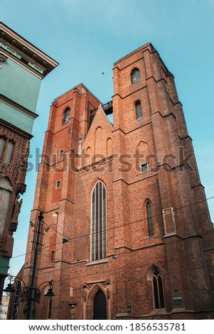 Tower of the old catholic church of red brick in the Gothic style on a background of blue sky
