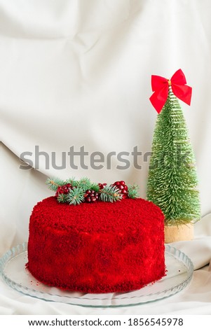 velvet cake decorated with evergreen tree and pomegranate seeds on a gray background