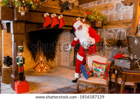 Santa Claus stands cheerful near the fireplace