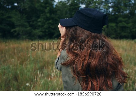 women in blue cap with loose hair in the meadow 