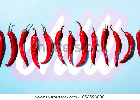 Top view of organic spicy peppers near chili lettering on blue