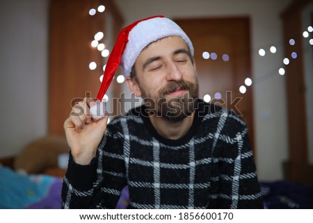 A bearded man in a Santa Claus hat. The man smiles and enjoys the New Year. Close-up portrait of a European bearded man.
