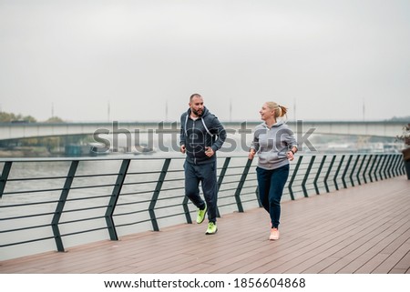 Young woman and man running in autumn day 