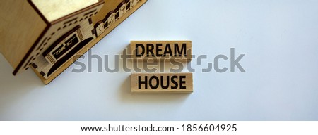 Wooden blocks form the words 'dream house' near miniature house. Beautiful white background. Business concept.