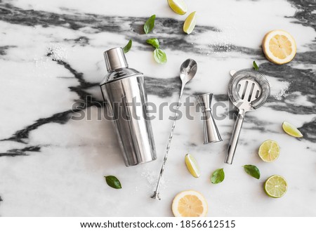 Cocktail set on the marble background - lemons, limes, shaker, spoon, ice