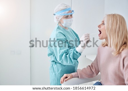 Middle-aged lady sitting with an open mouth during the sample collection for a PCR test Royalty-Free Stock Photo #1856614972