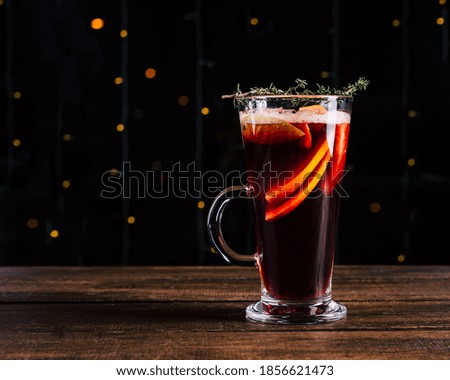 Delicious mulled wine in a glass against the background of garland lights