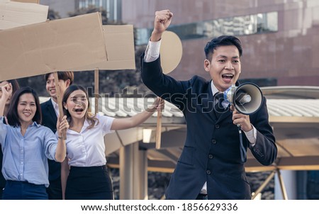 Focus on male leader of protestors shouting out for human rights with blank sign