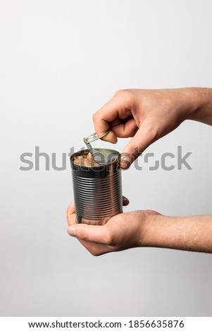 Man's hands opening a aluminum can full of cat or dog food, pate, grinned meat for pet food. Recycle materials, ecological