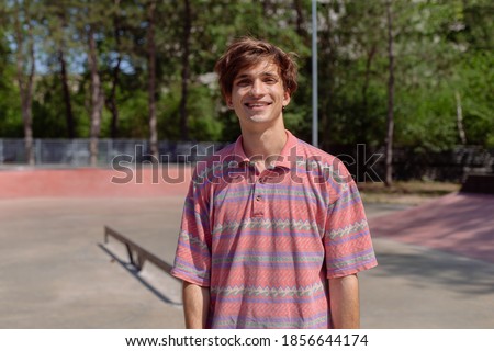 Closeup to the camera amazing man large beautiful smile in a modern skate park holding feeling happy she have hipster outfit