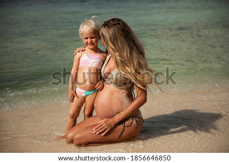 Pregnant woman and her daughter on the beach