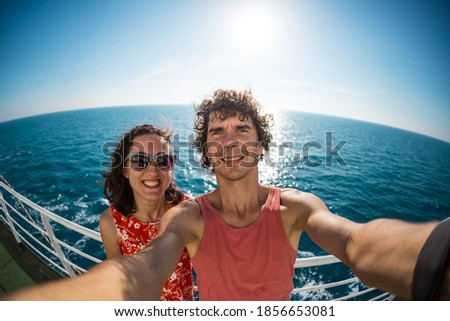 The family is sailing on a cruise ship, a girl with husband are standing at the fence on the ship and looking at the sea, traveling by ferry, a man with girlfriend take selfies on the ocean.