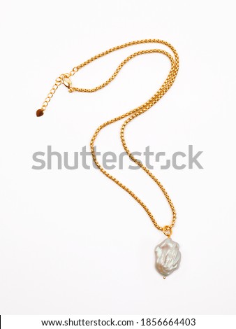 Luxury elegant golden chain with baroque pearl pendant isolated on white background. Close-up shot Royalty-Free Stock Photo #1856664403