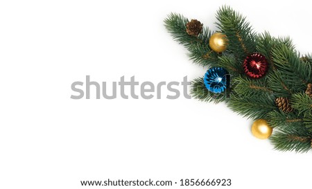 Spruce branch with cones and colored balls on white background