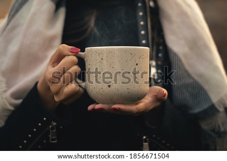Young woman holding a Cup of hot tea outside. Steam from a Cup of hot tea.