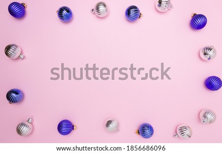 Christmas balls for decoration in blue and silver on a pink background on the edges in the form of a frame. Free space for text, top view.