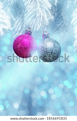 Decorative Christmas balls on frosty fir-tree branch over blue defocused lights