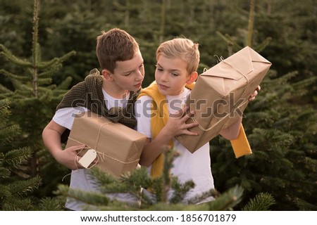 two boys with gifts in the fir forest. Christmas. European winter.