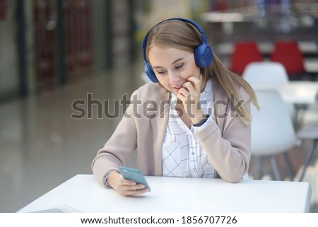 soft focus Portrait of a happy girl listening music on line with wireless headphones from a smartphone at white tables in a mall cafe. relaxation relaxation in the mall. Working outside the home