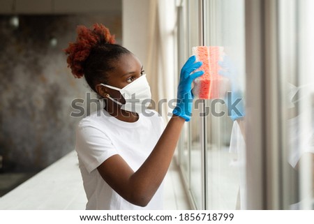young african woman in medical mask washing window
