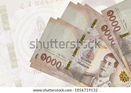 1000 Thai baht bills lies in stack on background of big semi-transparent banknote. Abstract presentation of national currency Royalty-Free Stock Photo #1856719132