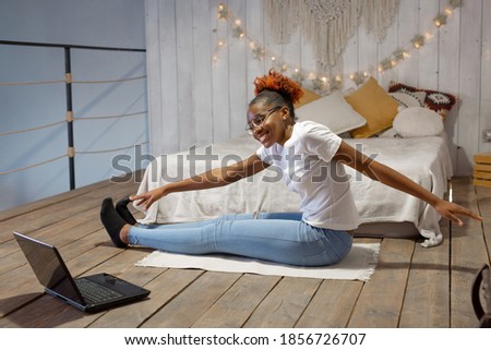 beautiful young african woman doing sports at home in front of laptop