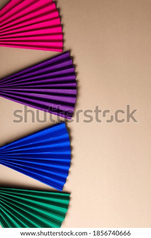 Vertical image.Top view of frame of paper fans on the beige background.Empty space