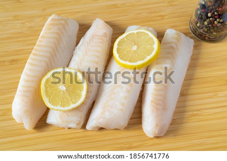 Frozen pieces of cod fish fillets or loins with slices of lemon.