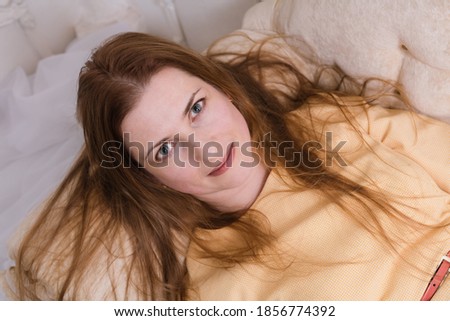 Attractive midle aged woman laying on sofa and looking up into the camera