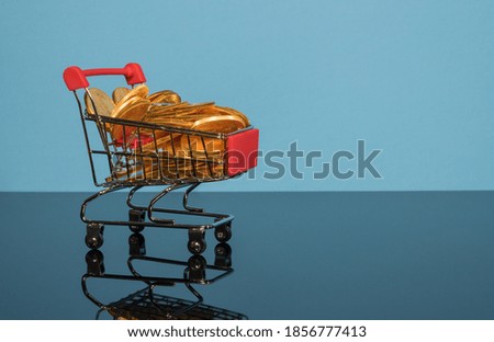 Mockup or concept background for winter sales with shopping cart filled with gold coins set against a blue background