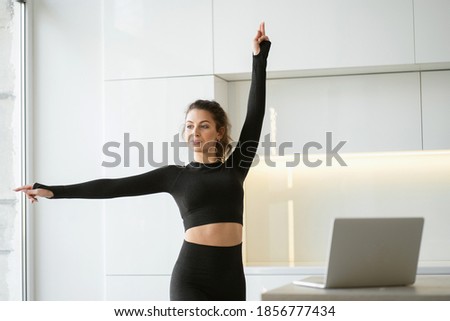 strong athletic brunette woman communicates via laptop computer with trainers online in a social network. does complex exercises body stretching fitness gymnastics aerobics. Royalty-Free Stock Photo #1856777434
