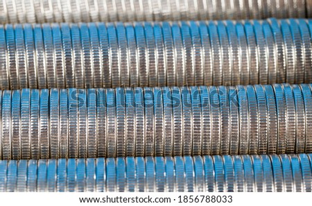 many round metal coins of silver color illuminated in blue, legal tender that is used for payments in the state, beautiful coins closeup blue hue, the same coin value
