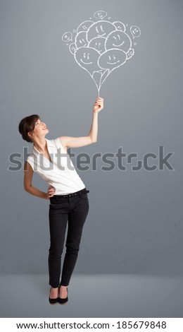 Happy young woman holding smiling balloons drawing